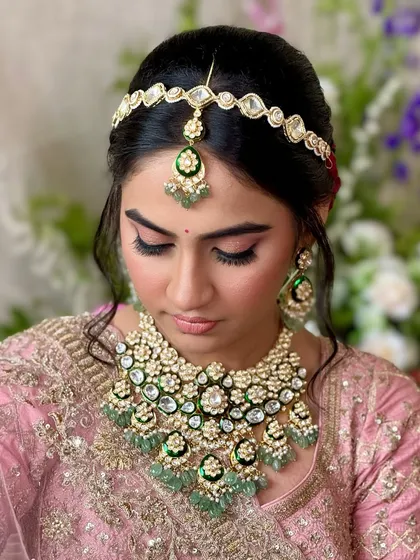 A detailed shot of the eye makeup and matha patti. The soft pink and shimmer on the lids make her eyes pop, while the jewelry adds a touch of tradition.
