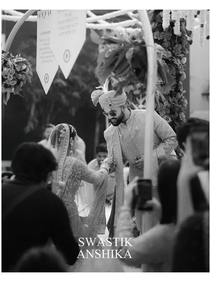 A candid black and white moment from the ceremony. This shot, taken from the perspective of a guest, captures the couple's connection and the reality of being surrounded by loved ones.