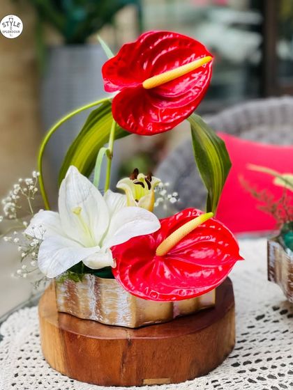 I love working with exotic flowers. This arrangement features striking red anthuriums and elegant white lilies on a wooden base, creating a modern and tropical centerpiece that commands attention.