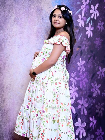 A beautiful side-profile portrait of the mother-to-be, showcasing her baby bump. The off-the-shoulder floral dress gives this maternity photo a light and airy feel.