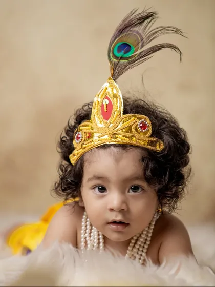 A simple and sweet portrait of a baby boy in his Krishna attire. The focus here is on his expressive eyes and the details of the peacock feather on his crown.