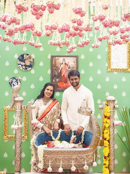 For little Tridha's naming ceremony, we designed a serene and traditional space. The backdrop features a classic pastel green with motifs, an antique silver cradle, and framed Ravi Varma paintings to create a timeless and elegant setting for the family.