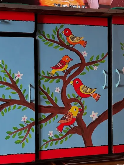 I gave this old cupboard a complete makeover with a vibrant, hand-painted mural. The design features colorful birds perched on a flowering tree, turning a functional piece of furniture into a statement art piece for the home.