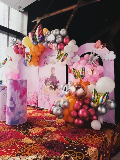 Another angle of the butterfly-themed rice ceremony decor, showing the full balloon arch and custom printed pedestals.