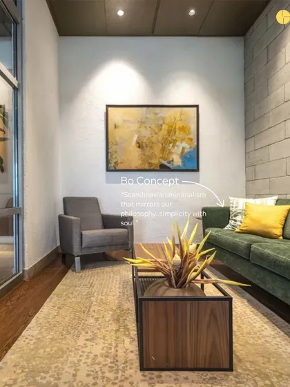 This seating area showcases our philosophy of "simplicity with soul." A comfortable green sofa from BoConcept is set against a concrete block wall, with a piece of abstract art adding a layer of intellectual curiosity to the space.