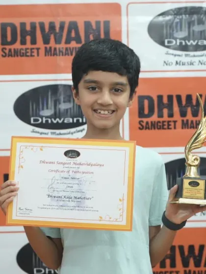 A beaming student holds up his certificate and trophy, a symbol of his dedication.