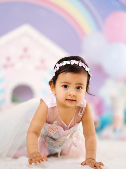 An adorable close-up of a baby girl during her first birthday photoshoot, crawling towards the camera with an inquisitive look.