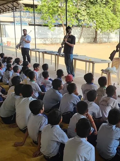A group of students seated on the ground, listening intently as my coaches explain the parts of a rifle. Foundational knowledge and safety are the first things I teach at these workshops.
