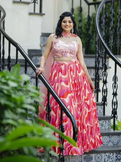 This Haldi hairstyle features natural curls in a half-updo, adorned with a small floral accessory. It's a fun, fresh, and practical style that keeps the hair managed during the ceremony.