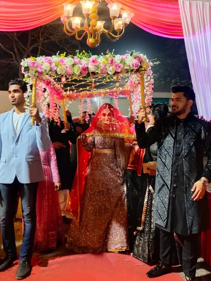 A bride entering under a Phoolon ki Chadar decorated with fairy lights, perfect for an evening ceremony. The lights add a magical sparkle to her entrance.