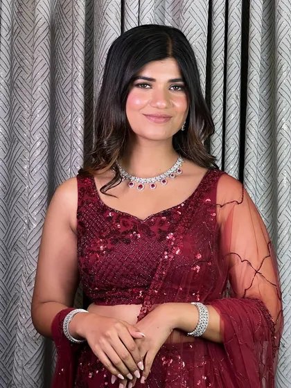 A full view of the reception party glam. The rich red outfit is perfectly complemented by the glowing makeup and soft, face-framing curls.