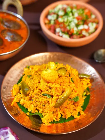 A close-up of flavorful Masale Bhat, a spicy Maharashtrian rice dish, served on a traditional copper plate. The rich colors and textures are highlighted, making the dish look incredibly appetizing.