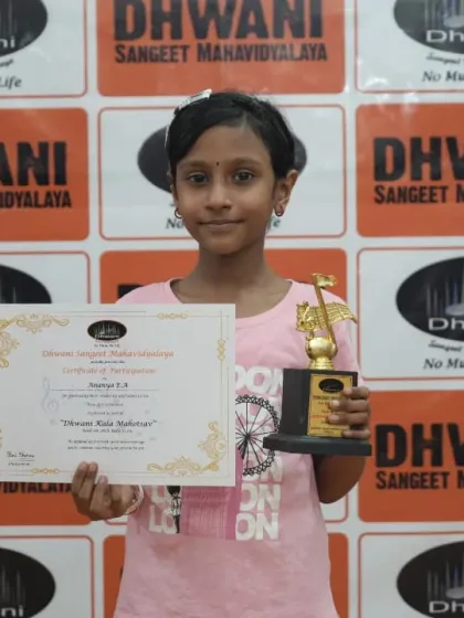 A young student proudly holds her certificate and trophy.