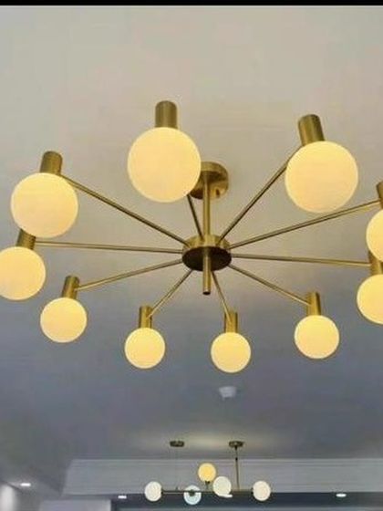 A semi-flush mount ceiling light with ten arms and frosted globes. This Art Deco inspired piece in a soft gold finish brings a touch of modern fashion to rooms with lower ceilings.