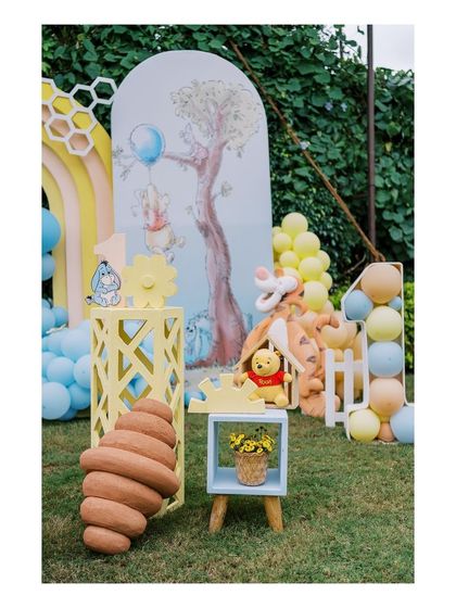 Details from the Hundred Acre Wood, including a Tigger prop, a beehive, and a balloon-filled number '1', perfect for a first birthday.