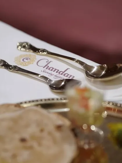 The little details matter. Custom-branded spoons placed on a crisp napkin next to a traditional Indian thali, adding a touch of personalized luxury.