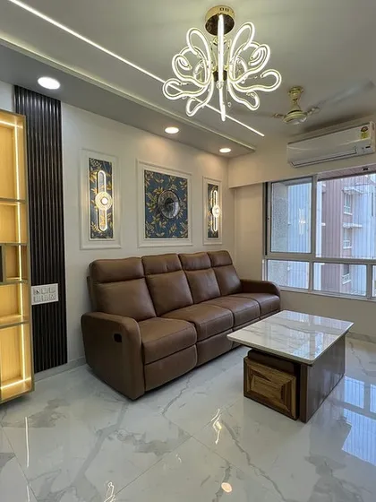A modern living room with a luxurious leather recliner sofa, marble-patterned flooring, and a striking chandelier, creating a high-end, comfortable space.