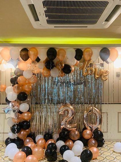 Another angle of the 20th birthday decor, showing how the balloon arch and scattered floor balloons fill the space. The color scheme of rose gold, black, and white offers a modern and chic party vibe.