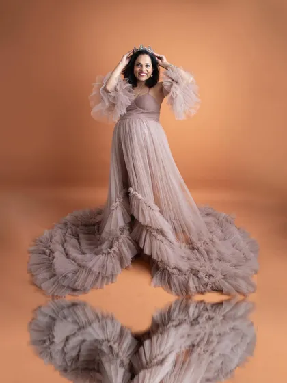 A stunning reflection shot. The mom-to-be, wearing a crown and a beautiful ruffled gown, looks like royalty in this creative and elegant portrait.