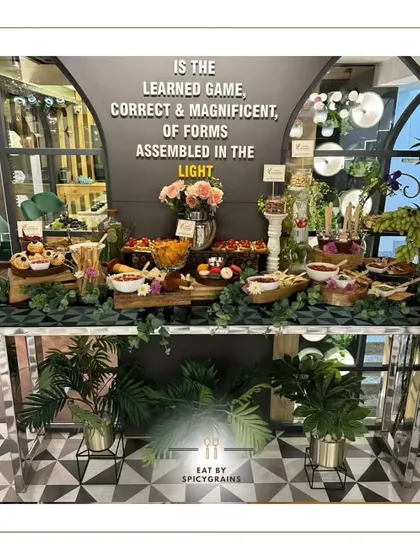 We love transforming spaces with our food. This grazing table was set up in a modern venue with geometric flooring, and we used sleek, metallic stands and lush plants to complement the contemporary aesthetic.