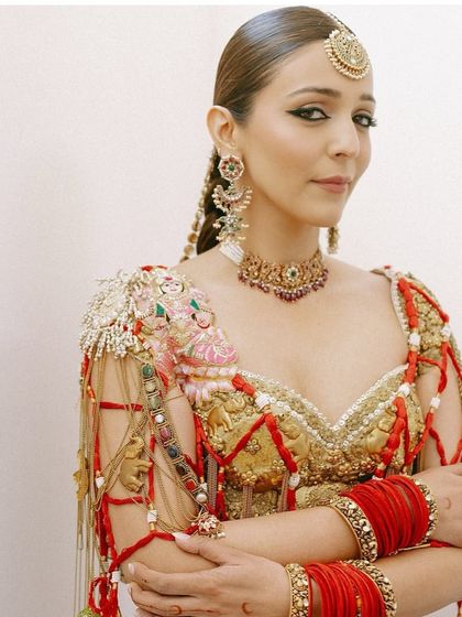 A close-up portrait of the bride, her sleekly styled hair and statement braid complementing her bold makeup and jewelry.