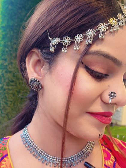 A close-up of a delicate silver matha patti with small flower motifs, paired with a simple choker and stud earrings.