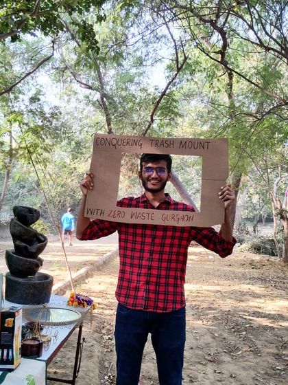 A proud volunteer frames himself with our "Conquering Trash Mount" sign. This captures the spirit of our community and our shared goal of reducing waste.