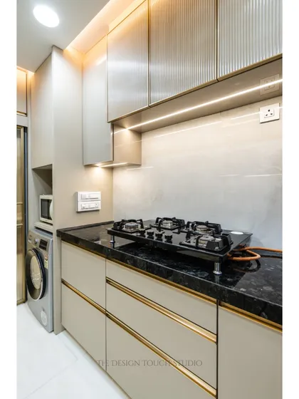 The cooking area features a black granite countertop and a modern hob. The fluted glass upper cabinets add texture and visual interest while providing stylish storage.