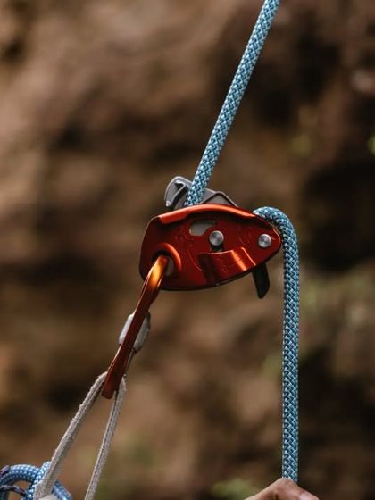 A close-up of a belay device, a critical piece of safety equipment for roped climbing. We teach you how to use different types of devices correctly and safely.