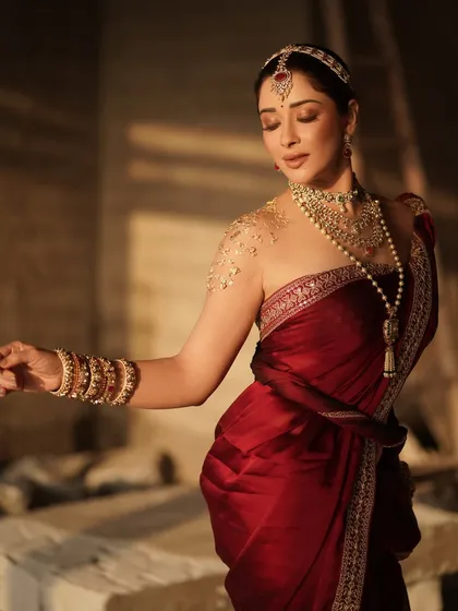 A candid, graceful pose from our shoot with Nyra Banerjee. This image captures the flow of the saree and the elegance of the layered pearl and gold jewelry, showcasing a timeless Indian beauty aesthetic.
