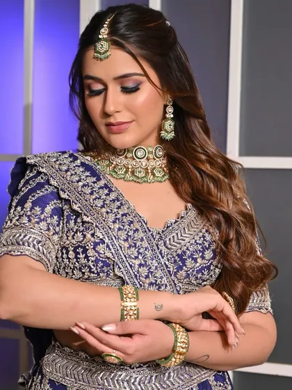 A graceful pose that highlights the intricate details of the lehenga and jewelry. The makeup ties the whole look together, creating a vision of festive elegance.