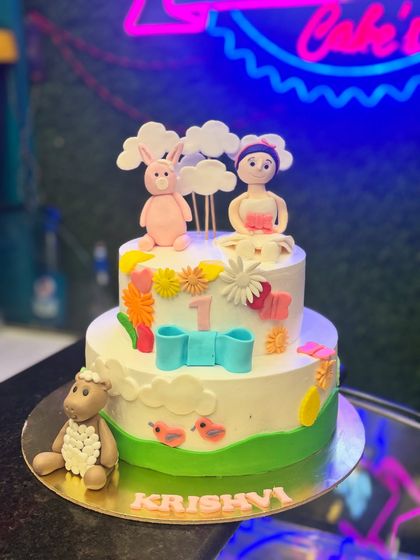 A two-tier cake with adorable, handcrafted fondant animals like a bunny and a sheep. This cake is perfect for a first birthday, with soft colors and a gentle, storybook feel.