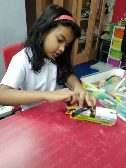 A girl concentrates on building a complex model, demonstrating the focus required in our robotics classes.