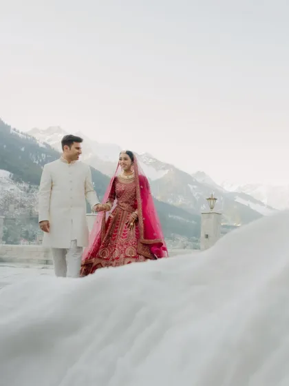 Walking in a winter wonderland. The couple holds hands amidst the snow, their colorful wedding attire creating a striking contrast. This shot highlights the beauty of a non traditional wedding season.