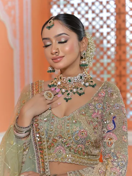 A perfect example of how jewellery can elevate a look. This stunning Polki and green gemstone choker set contrasts beautifully with the pastel green lehenga. This is a popular choice for brides who want a traditional feel with a touch of modern color.