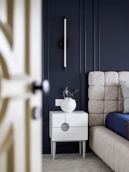 Another angle of the guest bedroom, highlighting the elegant wall-mounted light fixture and the custom bedside table with its unique circular cutout handle.