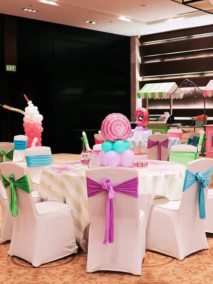 The guest seating area at the Candyland party. Each table had a unique centerpiece, like a balloon lollipop or ice cream sculpture, and chairs were decorated with multi colored sashes.