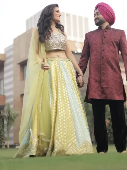 A lovely couple posing in our rental outfits. She wears a lime green and blue lehenga, while he complements her in a maroon Indo-Western kurta.