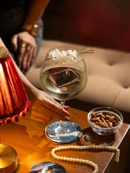 A sophisticated martini with a unique garnish. The lighting is designed to feel like an intimate evening at a chic bar.