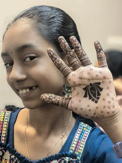 A minimal design for a young client. The back of the hand features a simple lotus motif with dotted patterns, and the fingers have delicate floral bands.