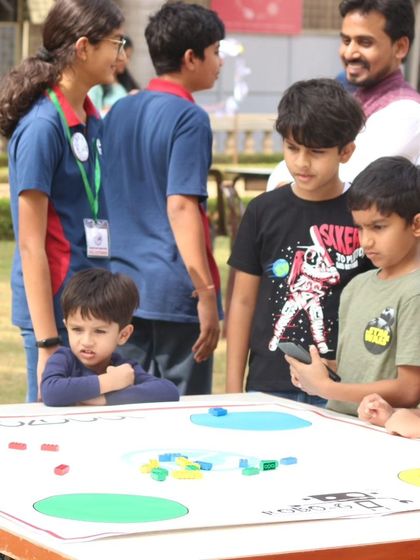 Children gather around a challenge table at one of our outdoor events, getting a hands-on introduction to robotics concepts.