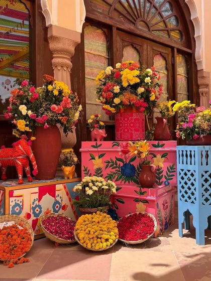 A corner decorated with hand-painted trunks and colorful floral arrangements. This artistic and traditional setup adds a touch of Rajasthani charm to the event.