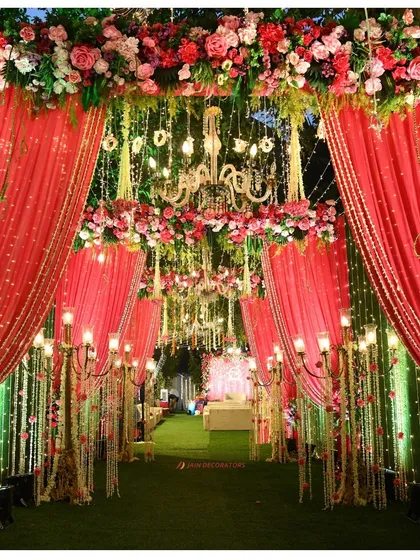 An entrance fit for royalty. I used dramatic red drapes, floral arches, and grand candelabras to create a luxurious and theatrical walkway for an opulent wedding celebration.