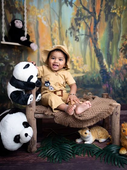 A big, happy smile from our jungle boy. The painted forest backdrop and props create a fun and immersive safari theme.