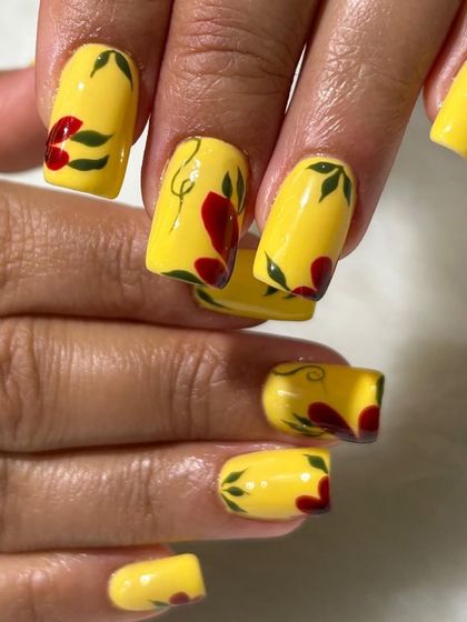 Sunshine on your fingertips! This bright yellow set on square nails is decorated with hand-painted red flowers and green leaves for a bold and cheerful floral look.
