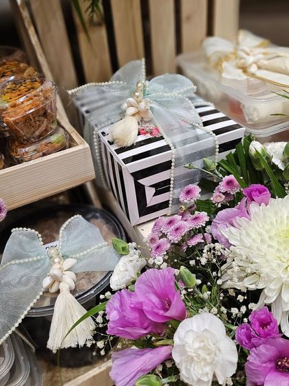 Details from the 70th birthday celebration hamper. I used elegant striped boxes and soft, tassel-adorned ribbons to complement the lush floral arrangements and gourmet treats.