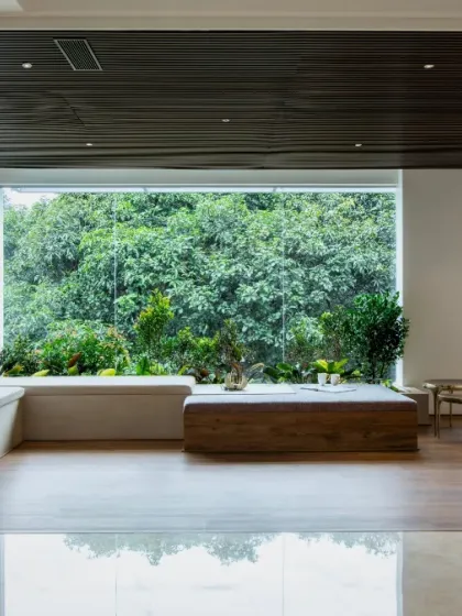 This lounge area is designed as a tranquil sanctuary where the boundary between inside and out disappears. A floor-to-ceiling window frames the dense forest, turning the natural landscape into a living piece of art.