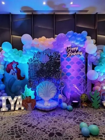 Dive into an underwater adventure with a Mermaid theme. This setup for a 3rd birthday includes a sparkling sequin backdrop, a custom seashell throne for the birthday girl, and balloon arrangements in ocean colors to create a magical under the sea experience.