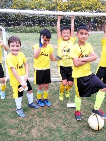 A group of happy players hanging from a goalpost. Teamwork and camaraderie are at the heart of the FAB experience.
