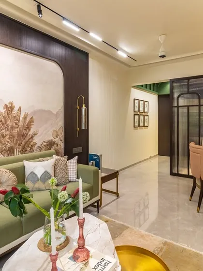 An open-plan living and dining area that feels both cohesive and distinct. The statement wallpaper acts as an anchor for the living space, while the green sofa adds a refreshing touch of color that connects with the natural theme.